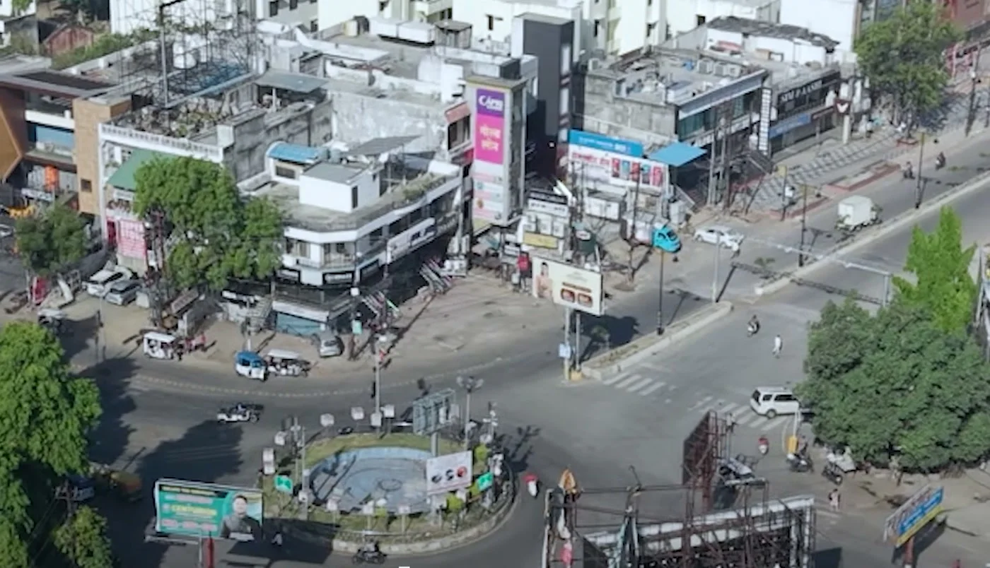 The Mahanagar crossing from the air, shops and traffic around the roundabout
